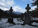 SX02789 Snow on celtic crosses in Glendalough with view to Lugduff mountain.jpg